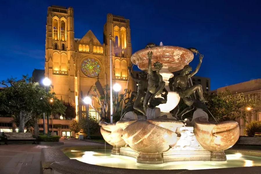 在格蕾丝大教堂 de São Francisco é retratada à noite 和 uma fonte de água ornamentada em primeiro plano.