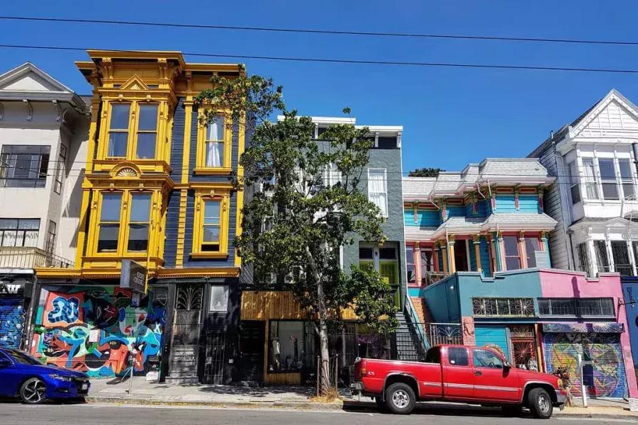 View of colorful buildings on Haight Street with cars parked along the Street. 圣弗朗西斯科，加州.