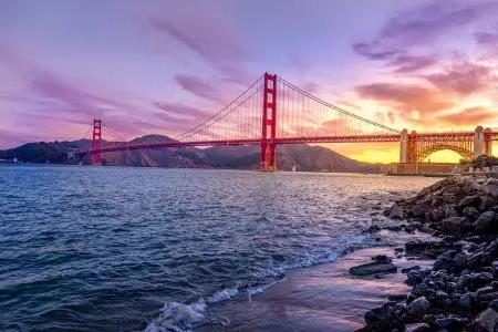 夕暮れ時のゴールデン ゲート ブリッジと、その前景に広がる色とりどりの空とサンフランシスコ湾。