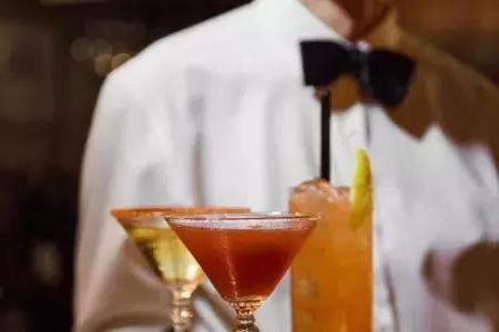 贝博体彩app的苦艾酒餐厅，系着领结的服务员递上鸡尾酒托盘。