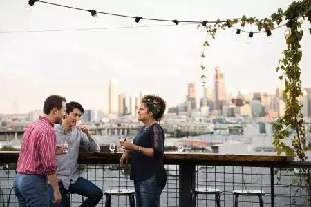 Three people gather around an outdoor table on the roof deck of Anchor Distilling in 贝博体彩app，加利福尼亚.