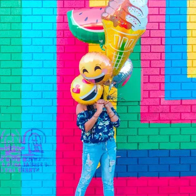 一个女孩在彩色壁画前用气球庆祝生日。。